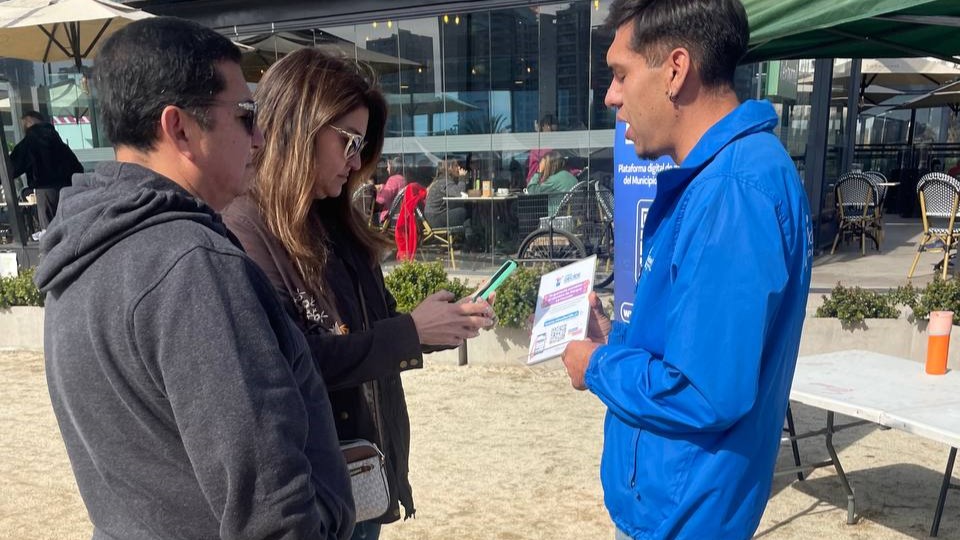 Persona en chaqueta municipal con dos personas más respondiendo una consulta